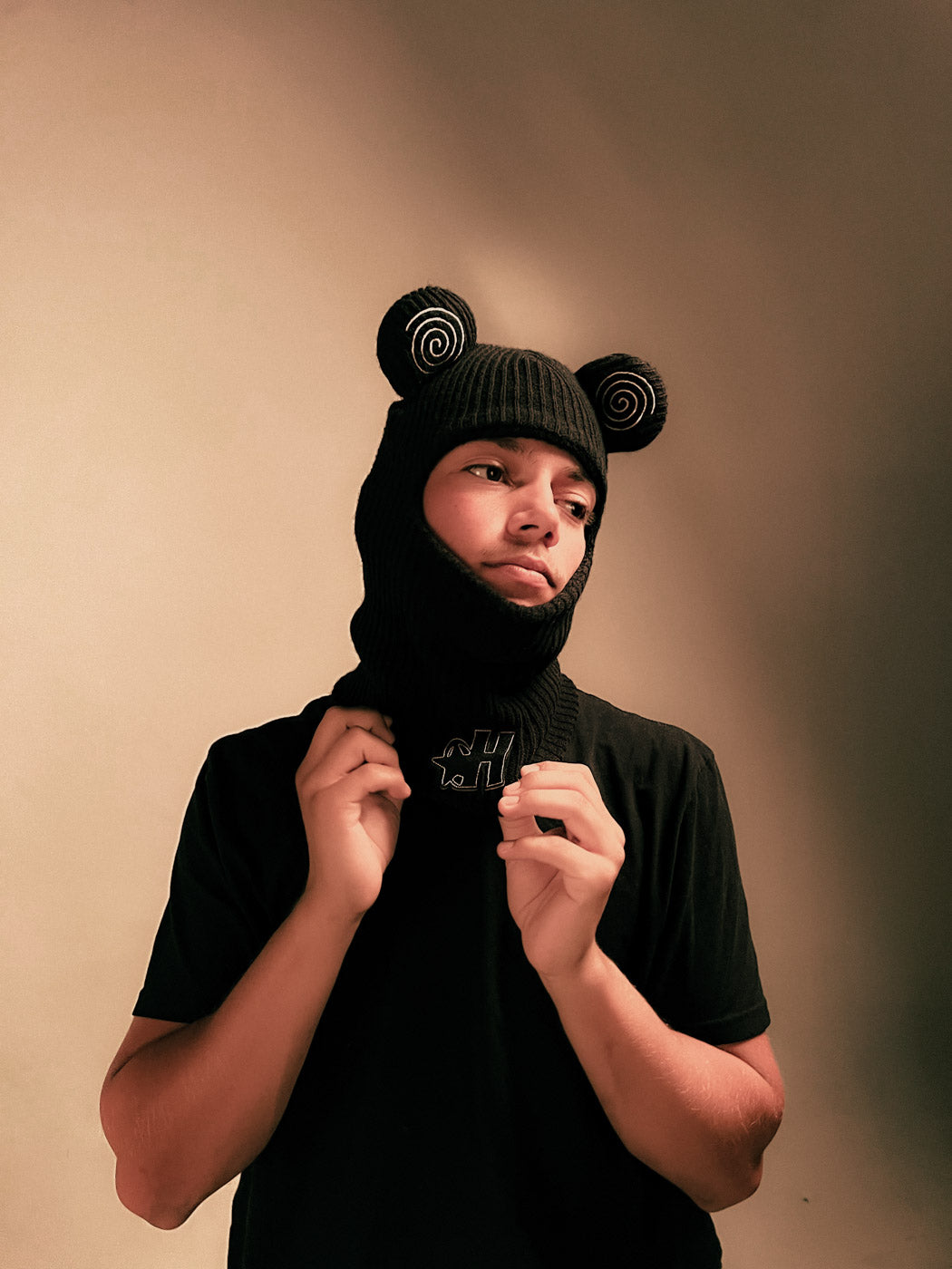 Model wearing the Hypnotic Clothing Spiral Balaclava with spiral ear details, studio streetwear portrait.