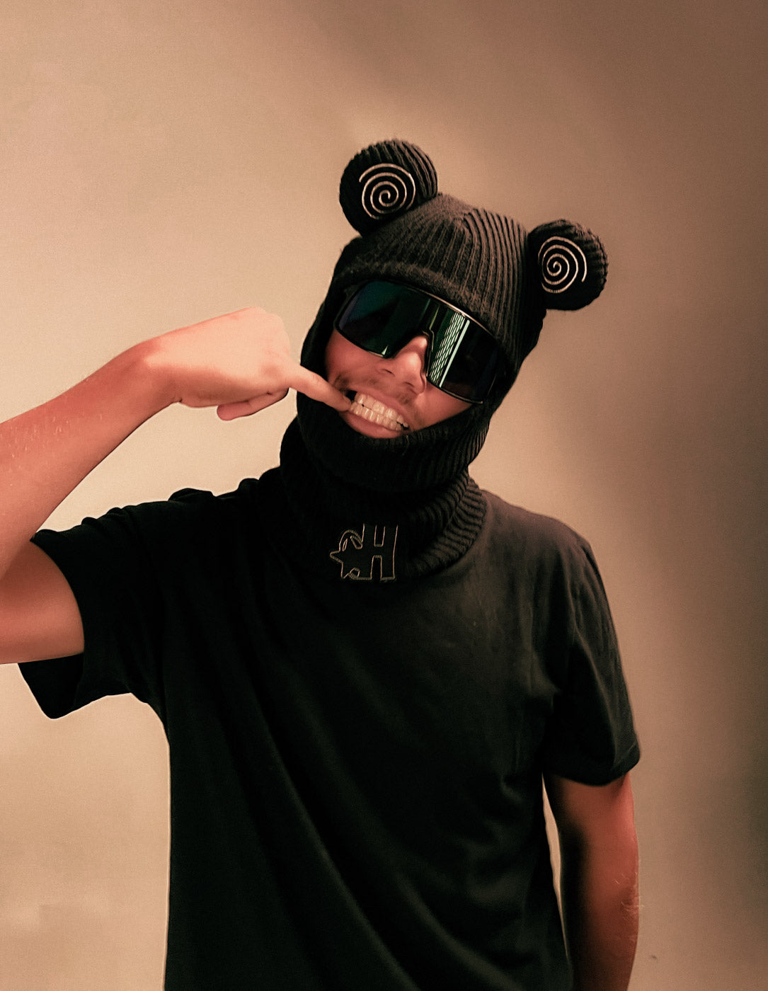 Model wearing the Hypnotic Clothing Spiral Balaclava striking a playful pose in studio, creative streetwear photography.