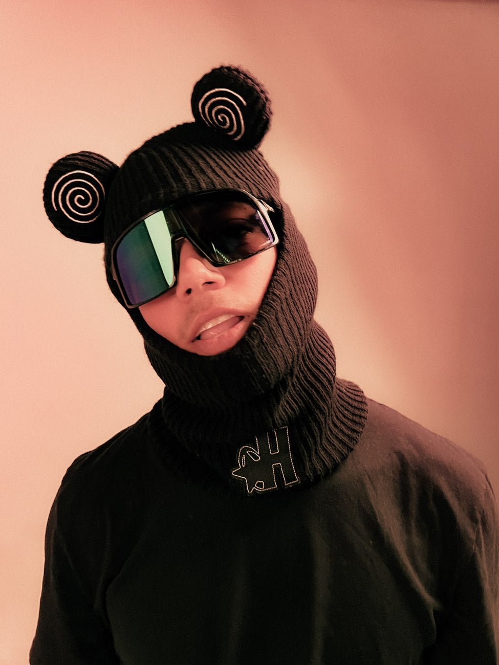 Model wearing the Hypnotic Clothing Spiral Balaclava and sunglasses in studio lighting, experimental streetwear look.