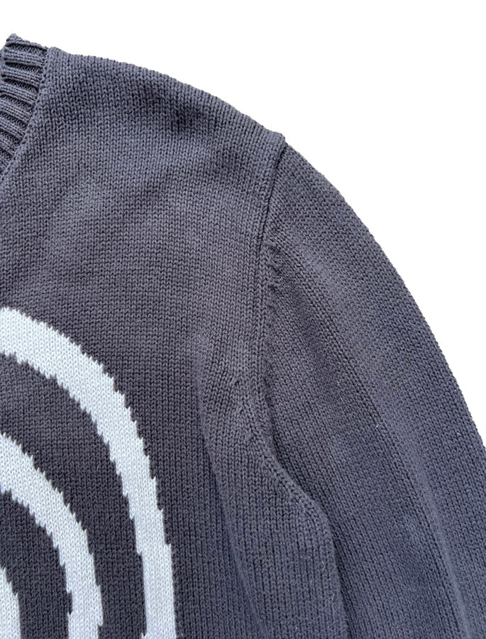 Detail shot of Hypnotic Clothing ‘Lost in the Matrix’ knit sweater showing shoulder seam and white spiral design.