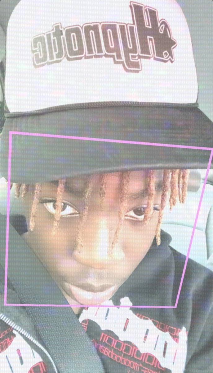 Model (Nimstarr) wearing Hypnotic Clothing printed logo trucker hat outdoors while looking down, paired with a black graphic tee.