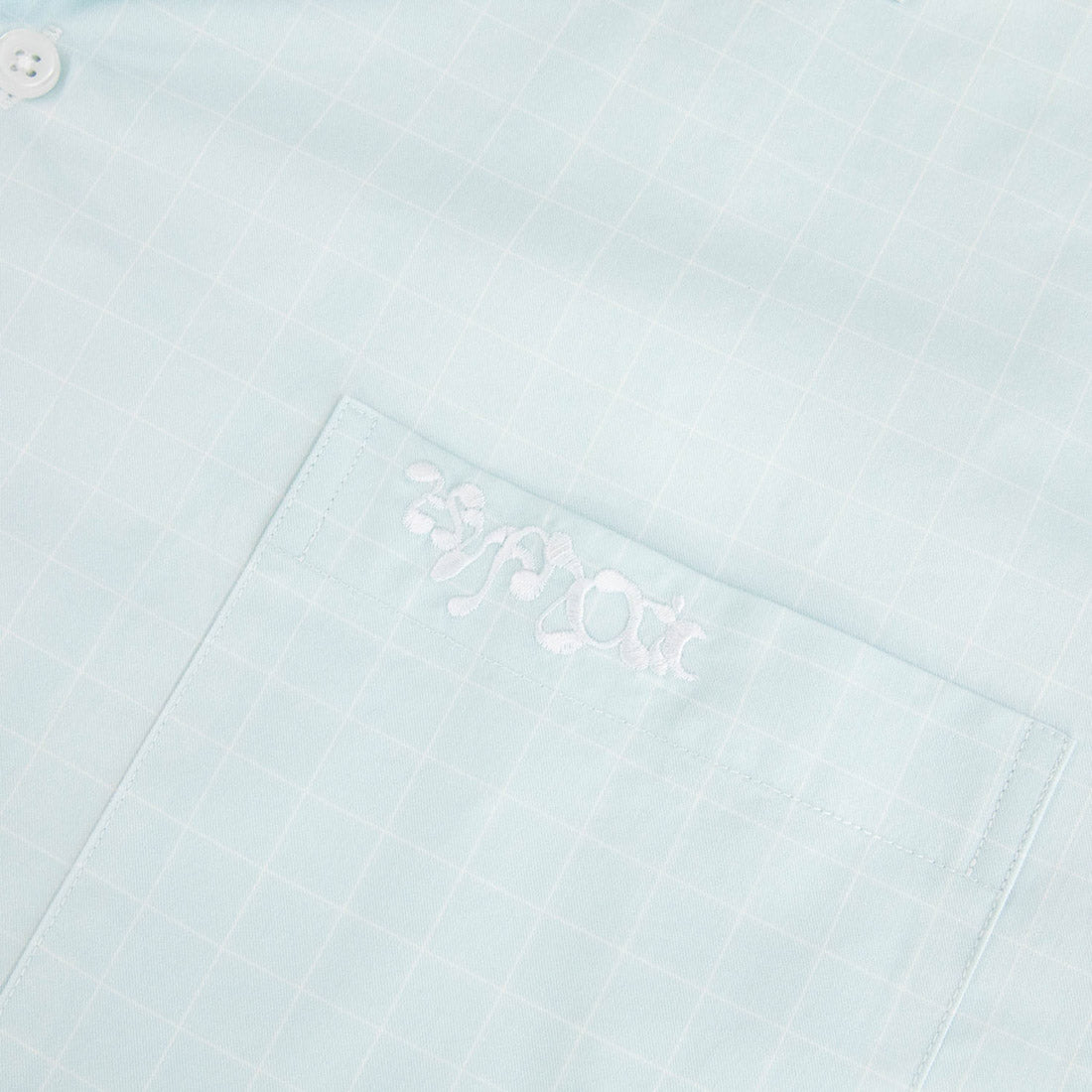 Close-up of Hypnotic Clothing HYP button-up shirt pocket with white embroidered logo on mint grid-pattern fabric.
