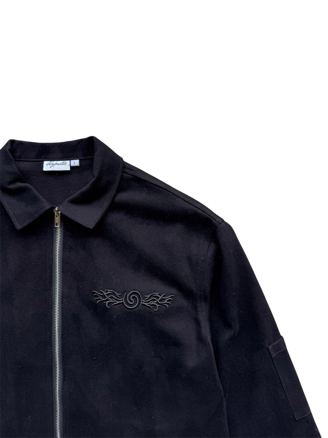 Close-up of the right side of the Hypnotic Clothing Lucien black work jacket showing embroidered details and arm side pocket, modern streetwear craftsmanship.