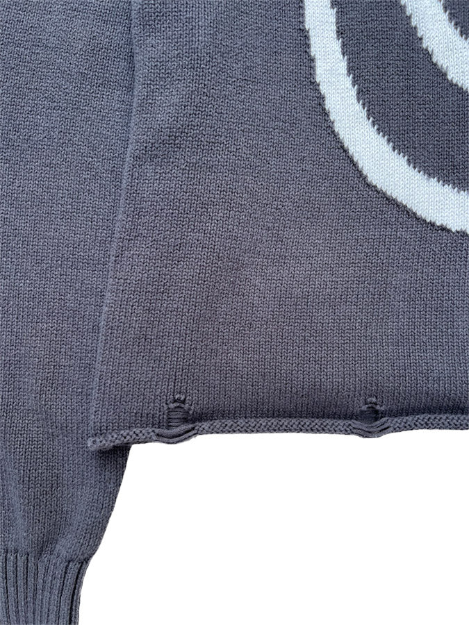 Close-up of Hypnotic Clothing ‘Lost in the Matrix’ sweater hem and knit texture in charcoal grey.